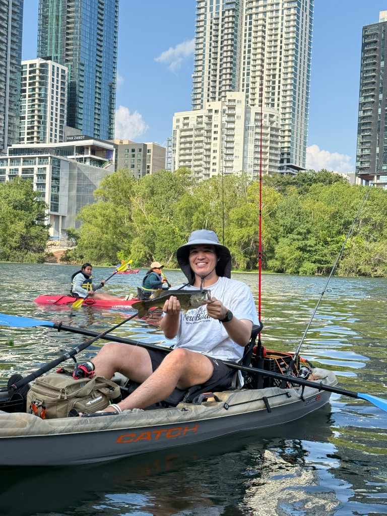Holding up a largemouth bass caught on Town Lake with the Austin skyline behind